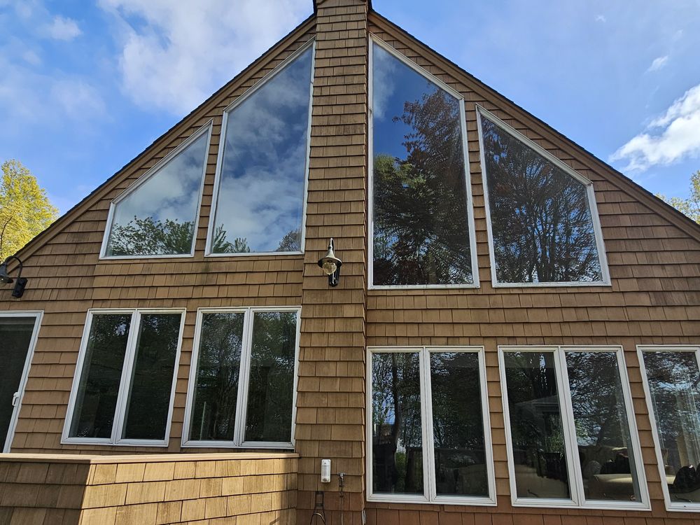 Cedar-shingle home with large filmed gable windows above a deck