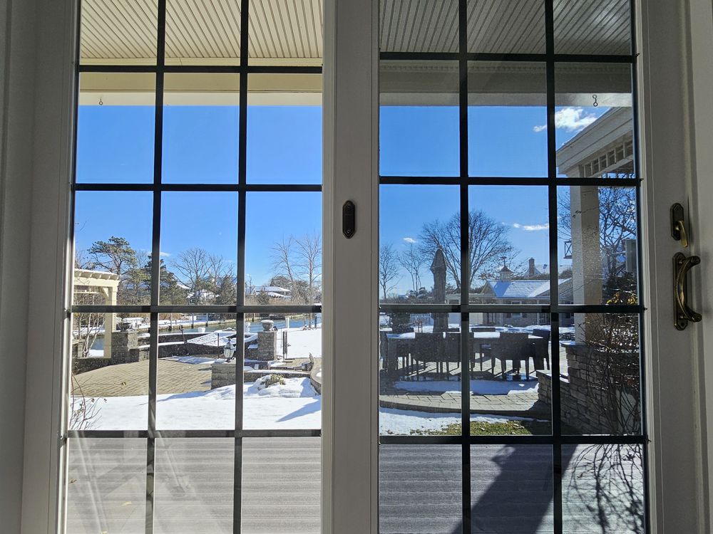 Filmed French doors in a Pellikal client's home looking out over a snow-covered waterfront terrace