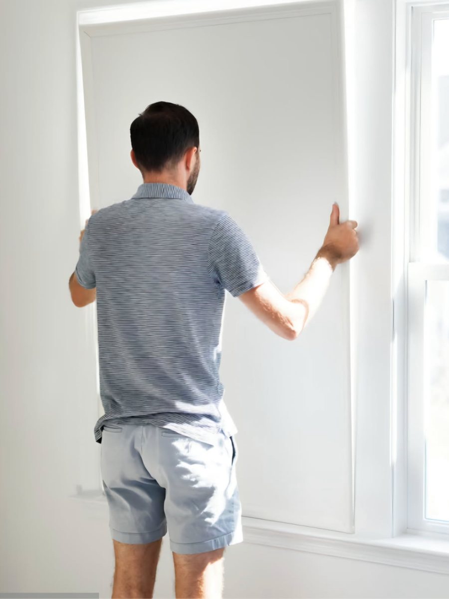 A person pressing a custom window insert into an existing window opening