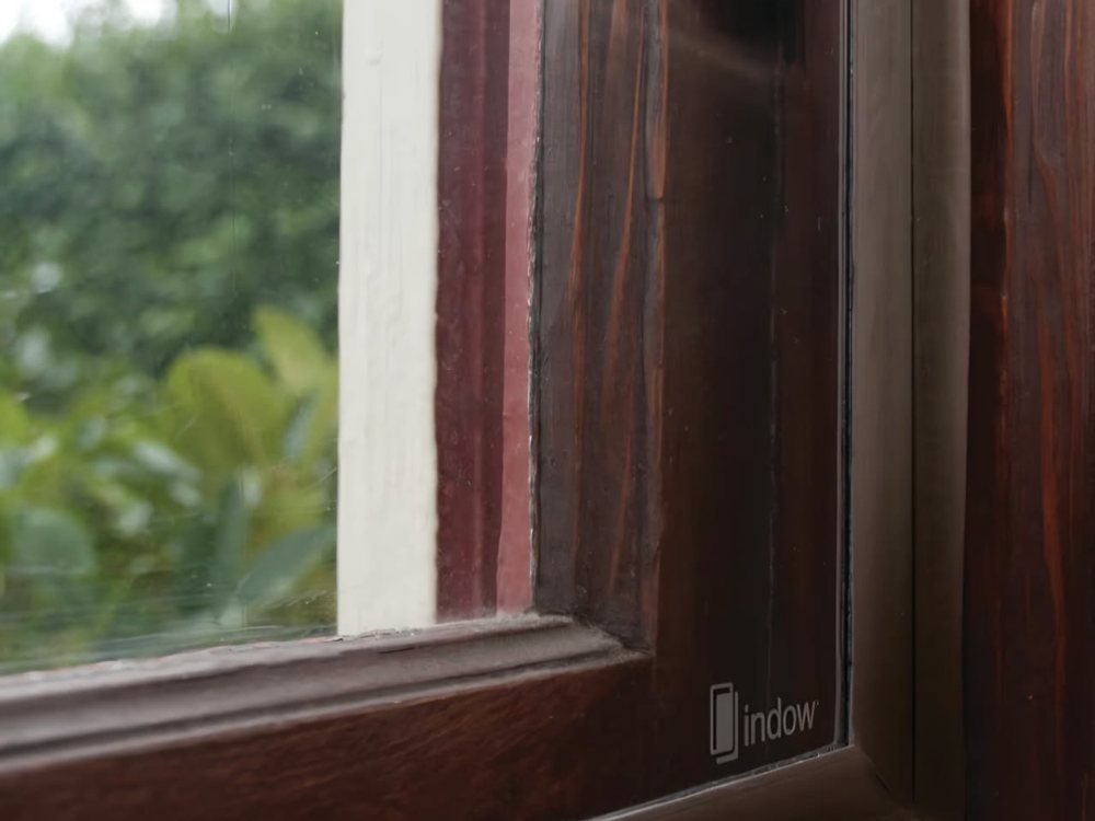 Close-up of an insert seated inside a stained timber window frame, showing the compression seal along the edge